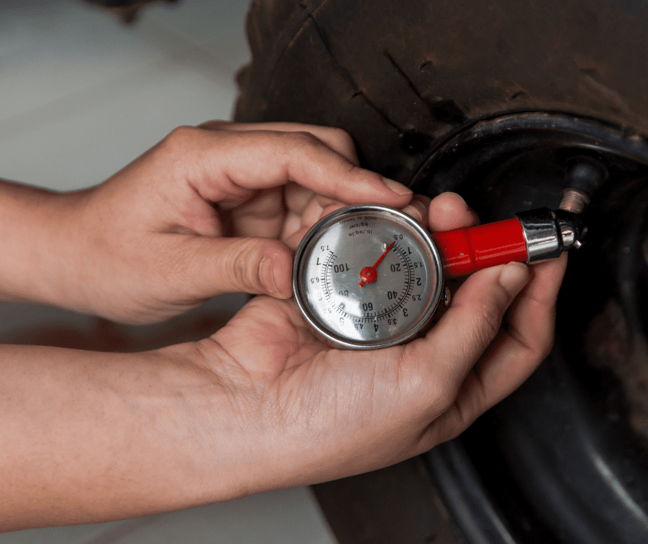Person checking tire pressure using a tire gauge